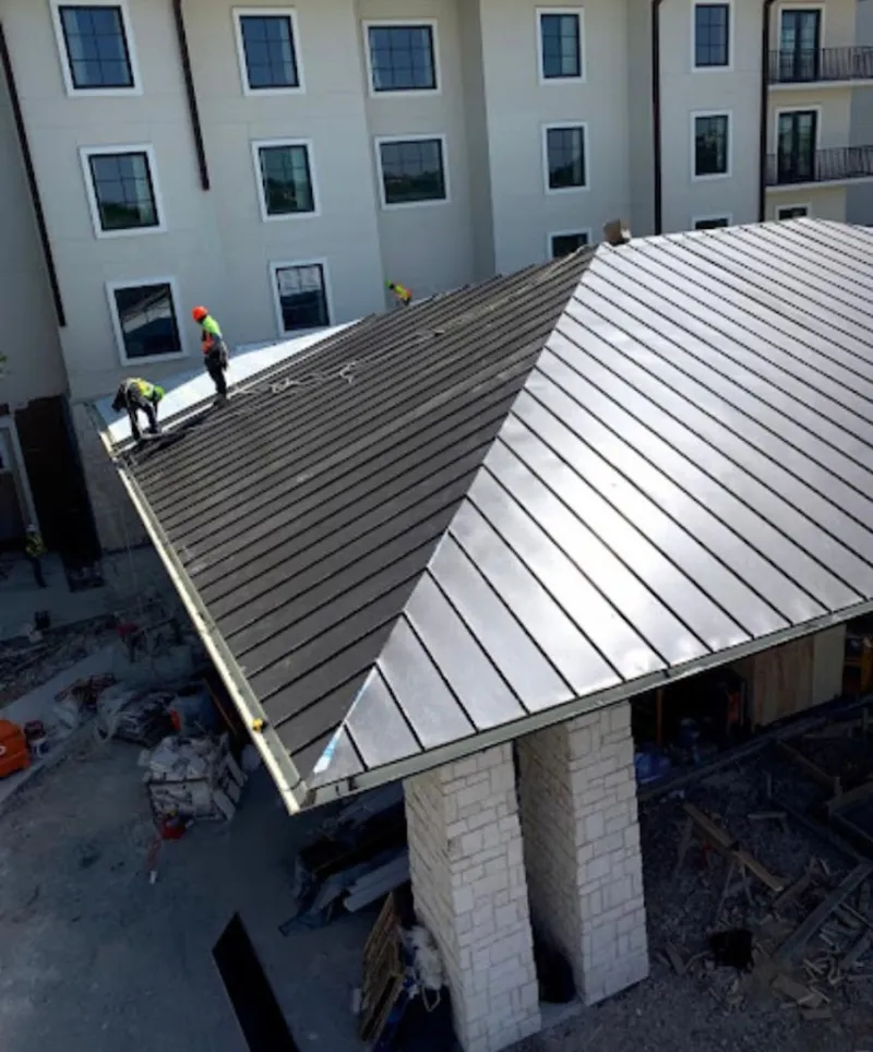 Crew installing standing seam metal roof panels on a commercial project in Wade Hampton